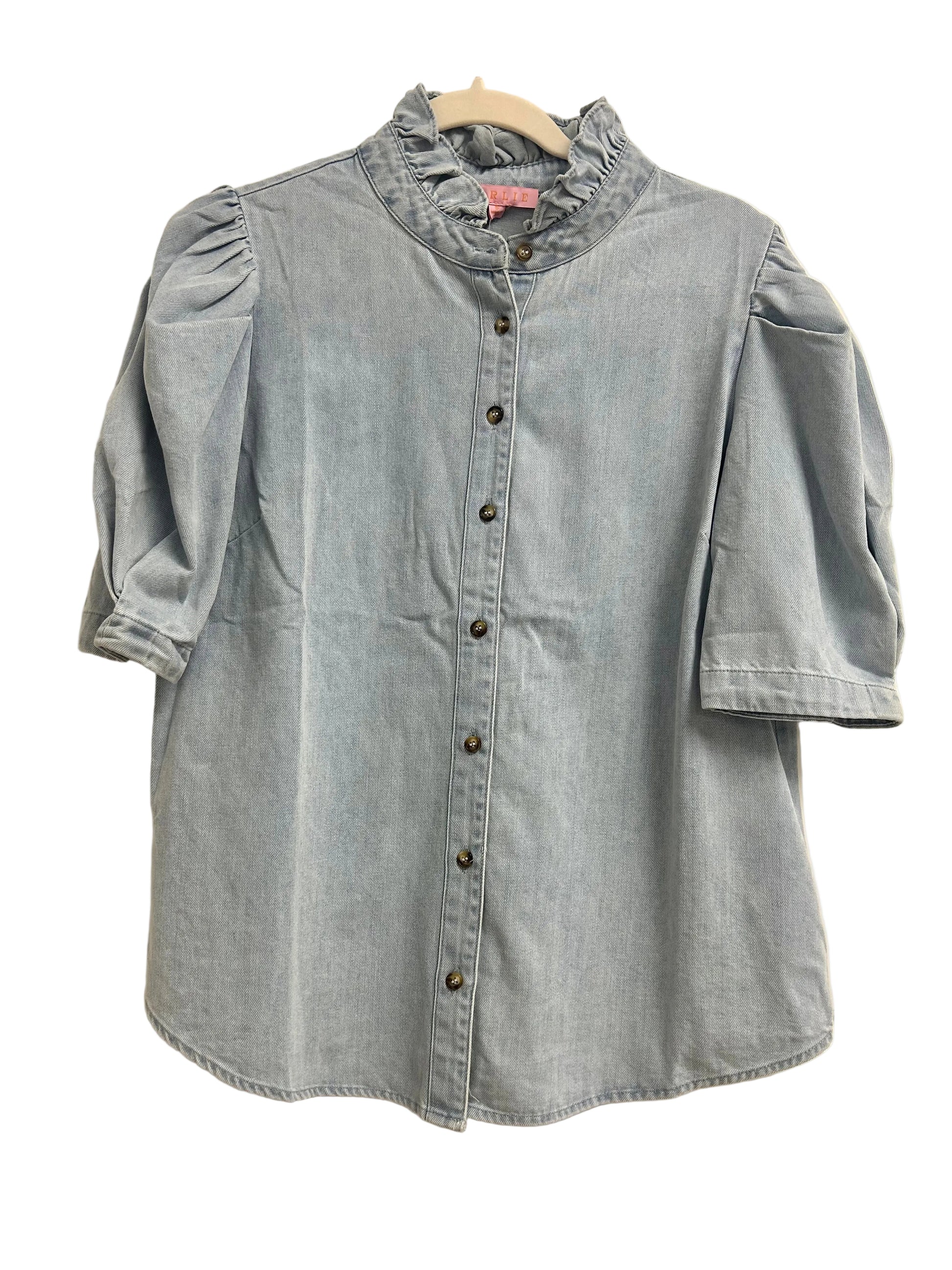 Light blue denim shirt on a hanger against a white door background