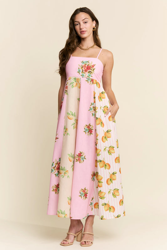 Woman wearing a pink floral and fruit patterned dress on a beige background